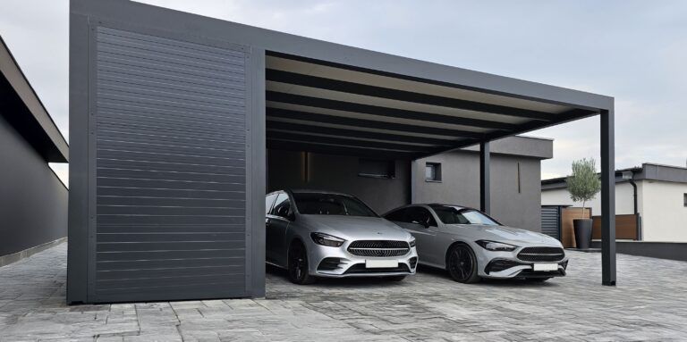 Anthracite aluminium Soltec carport with a slatted side panel, sheltering two cars on a paved driveway in front of a modern house