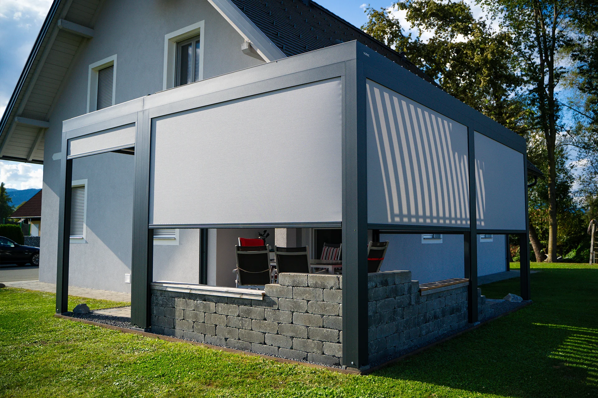 Bioklimatska pergola SL 170/28 z zaprtimi ZIP senčili ob hiši